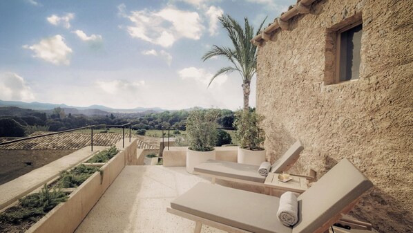 A terrace with lounge chairs, a palm tree, and a view of distant mountains. - Es Racó d’Artà, a Member of Design Hotels™ (Arta)