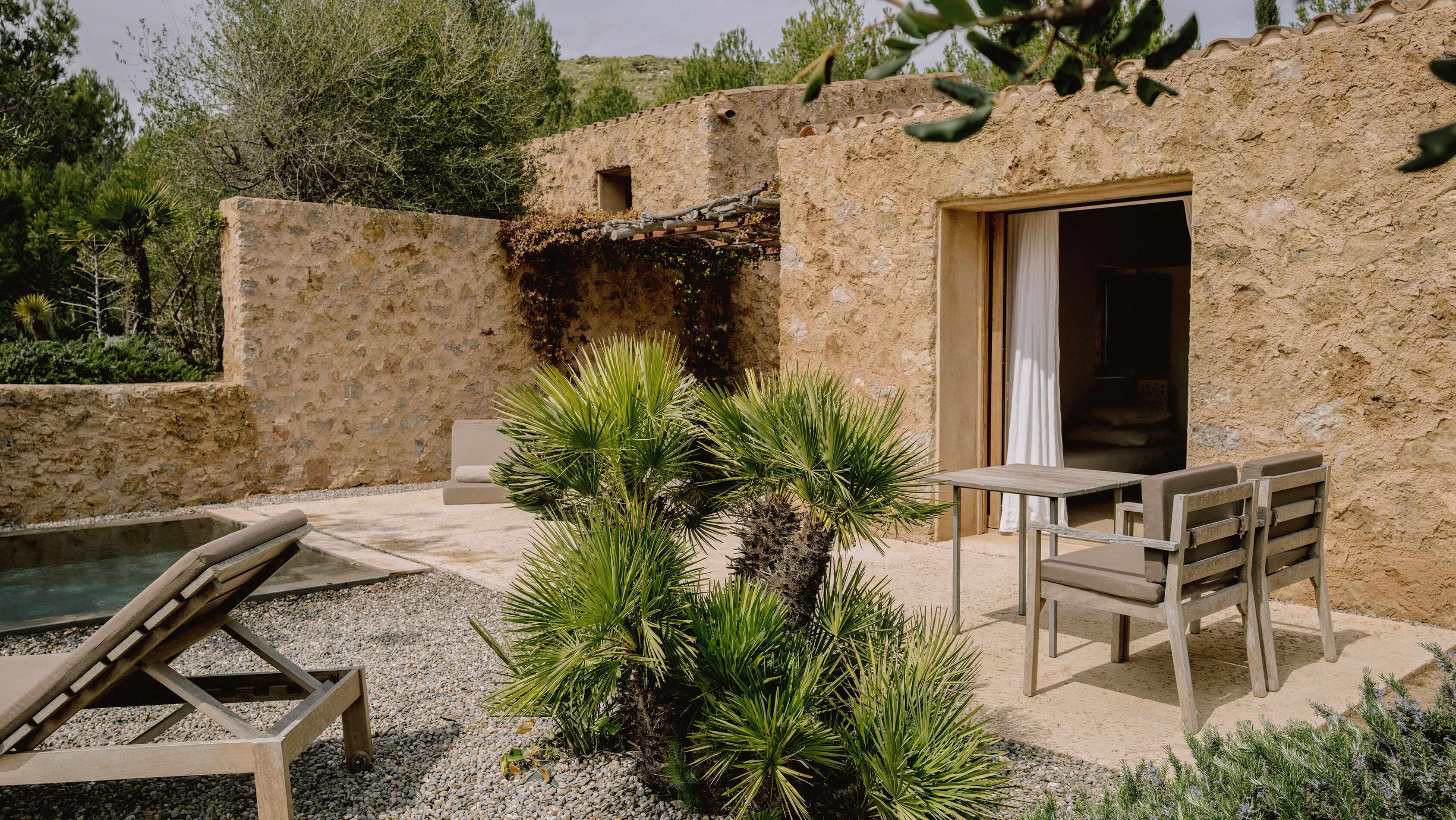 A rustic outdoor area with a pool, lounge chairs, and a table with benches.