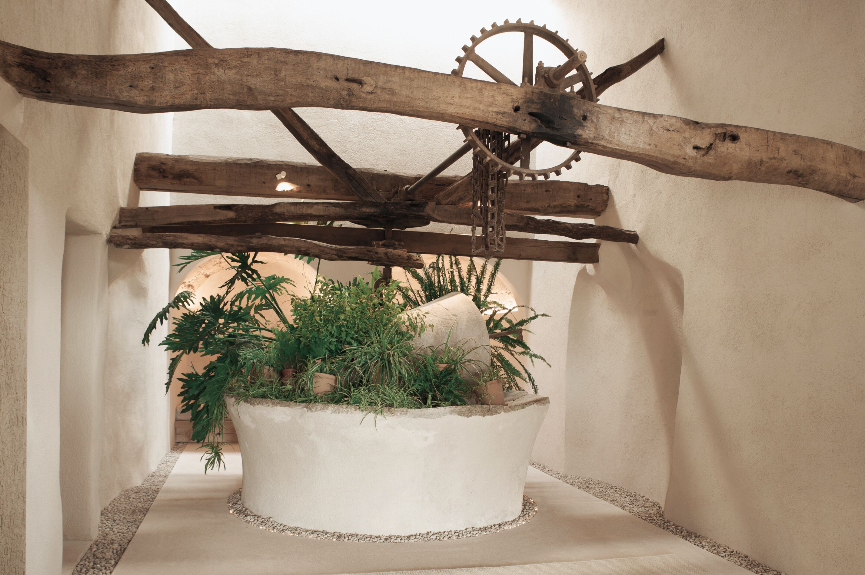 A rustic wooden structure with a large gear and a potted plant.