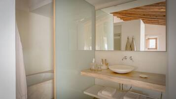 Un baño moderno con un espejo grande, un mueble de tocador de madera, un lavabo blanco y un perchero para toallas.