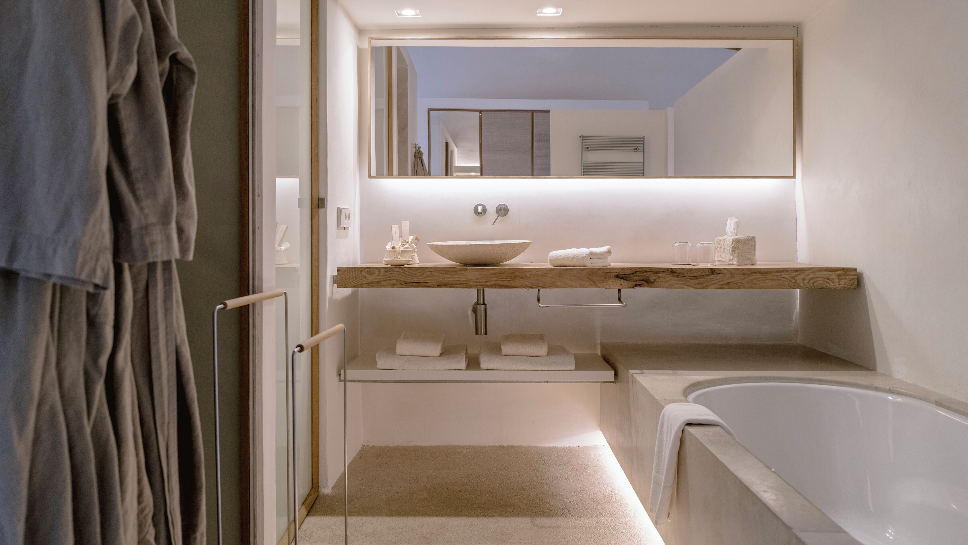 A modern bathroom with a wooden vanity, a large mirror, a bathtub, and a walk-in shower.
