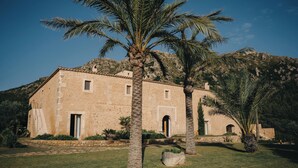 A stone building with a flat roof, surrounded by palm trees and a grassy area. - Es Racó d’Artà, a Member of Design Hotels™ (Arta)