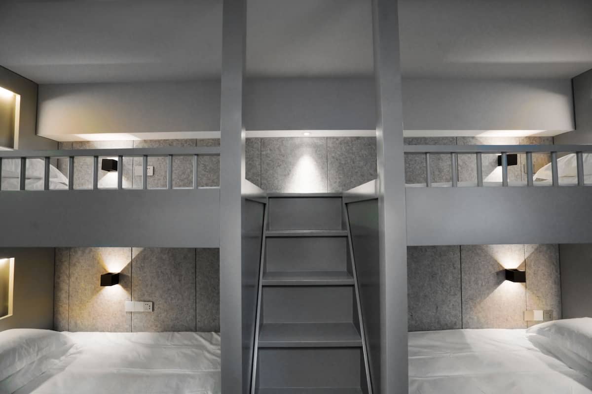 A modern hotel room with a central staircase, two beds, and built-in lighting.