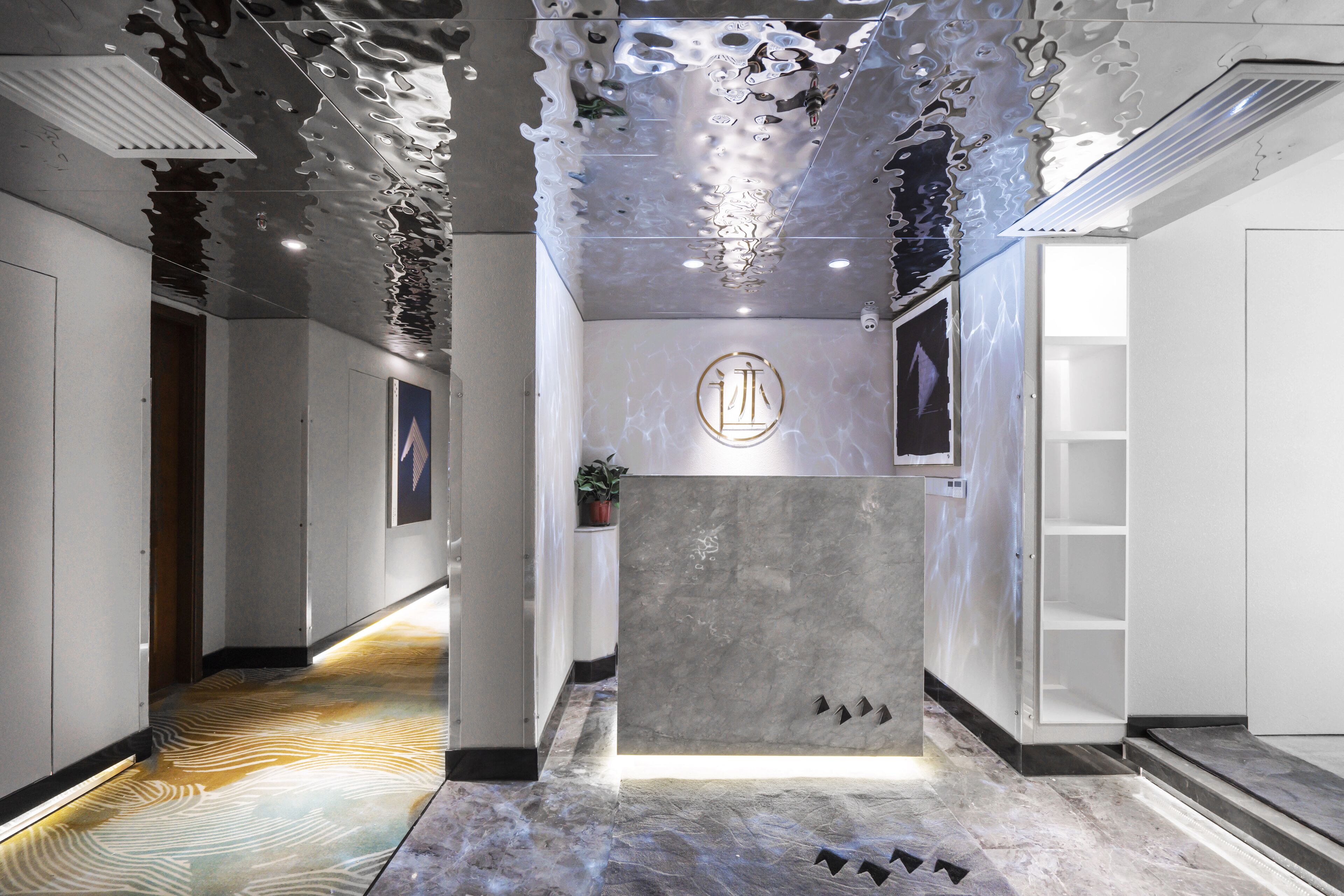 A modern reception area with a marble reception desk, a logo on the wall, and a patterned floor.