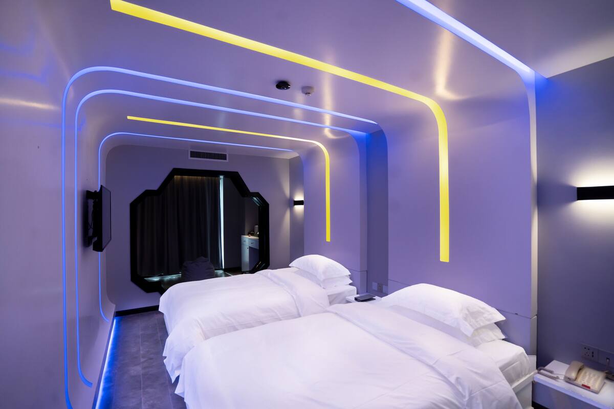 A modern hotel room with a neatly made bed, a bedside table, and a wall-mounted phone.