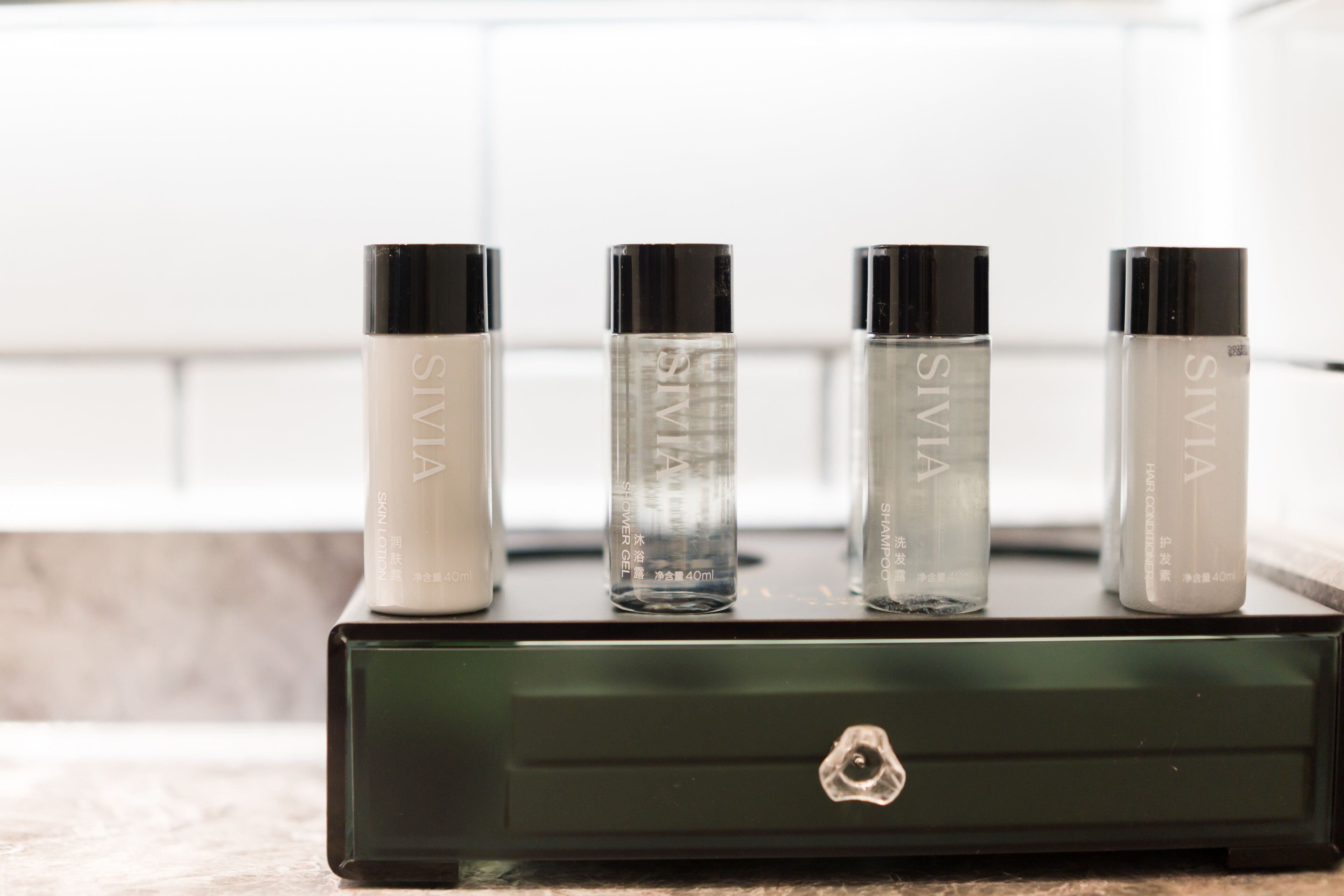 Four bottles of SIMIA shower gel on a black drawer.