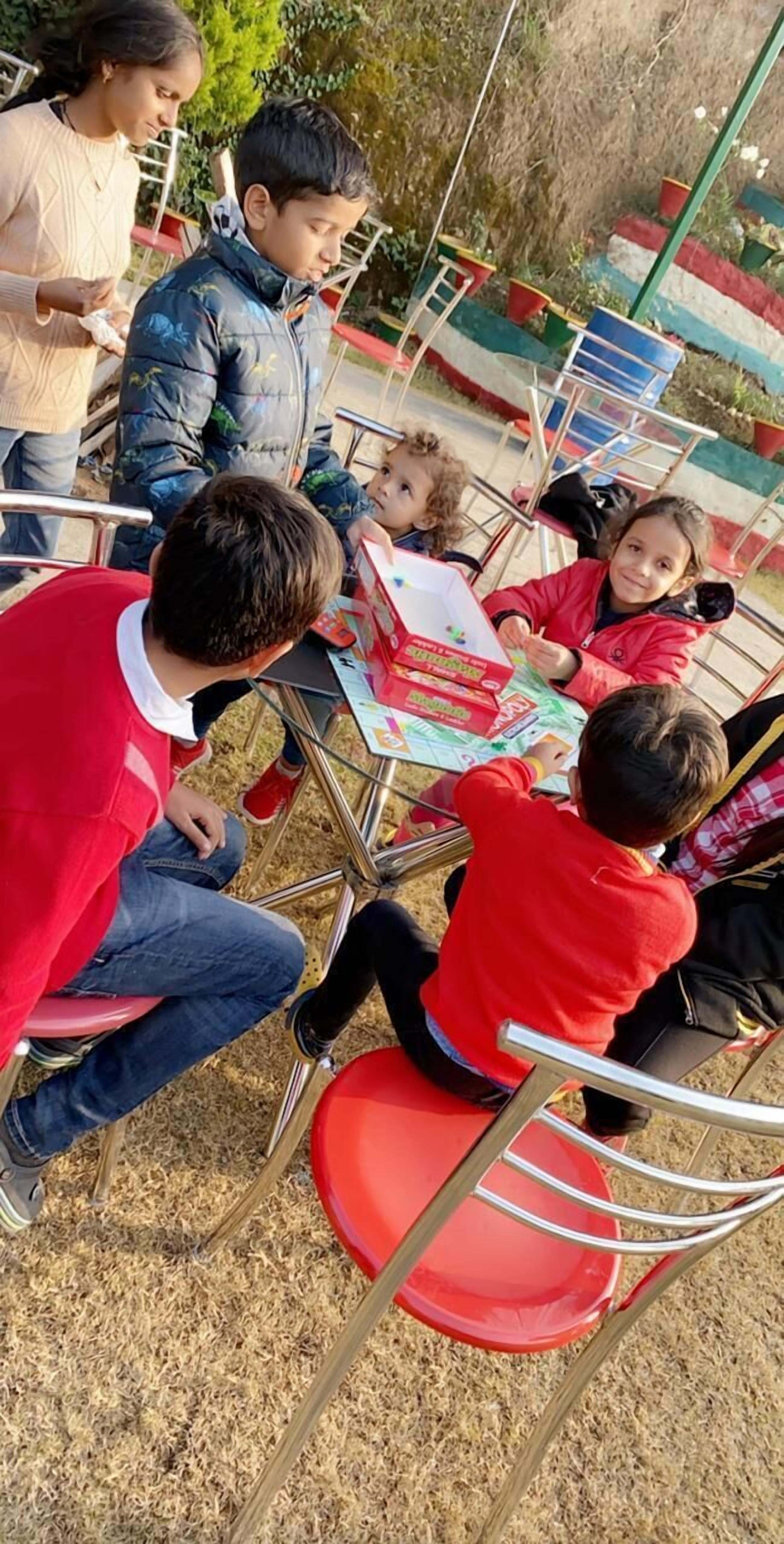Un grupo de personas sentadas en una mesa al aire libre, realizando una actividad con una caja y papeles.