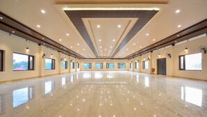A spacious, well-lit hall with a polished floor, large windows, and ceiling lights. - Nakshatra Resort Shimla (Arki)