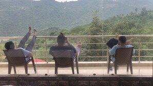 A group of people seated on chairs with a view of a mountainous landscape. - Nakshatra Resort Shimla (Arki)