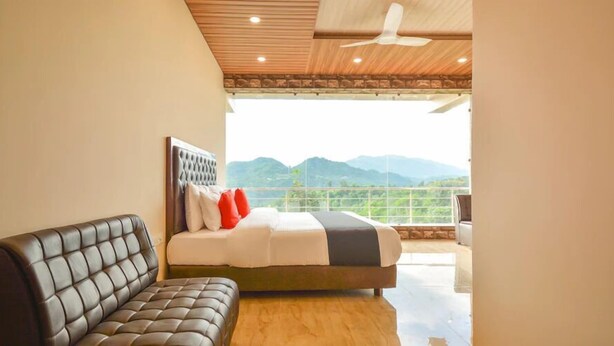 A bedroom with a bed, a sofa, and a view of mountains. - Nakshatra Resort Shimla (Arki)