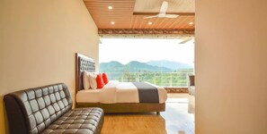 A bedroom with a bed, a sofa, and a view of mountains. - Nakshatra Resort Shimla (Arki)