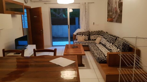 A living room with a wooden dining table, a sofa, and a TV. - Residence Zety (Abidjan)