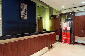 A reception desk with a wooden counter, a mirror, and a RedDoor's advertisement. - Reddoorz Plus Near Blok M Square (Jakarta)
