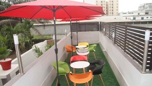 A rooftop terrace with colorful chairs and a red umbrella. - Villa Malis T6 (Abidjan)
