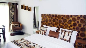 A hotel room with a large bed, a chair, a desk, and a mirror. - Villa Malis T6 (Abidjan)