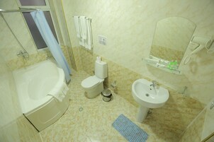 Un baño con bañera, inodoro, lavabo y espejo.