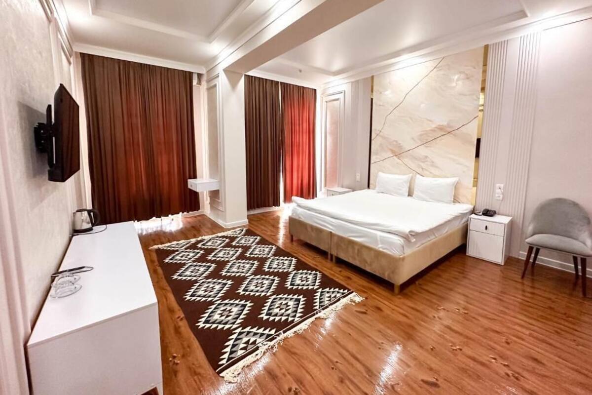 Un dormitorio moderno con una cama grande, un escritorio, una silla y un televisor.