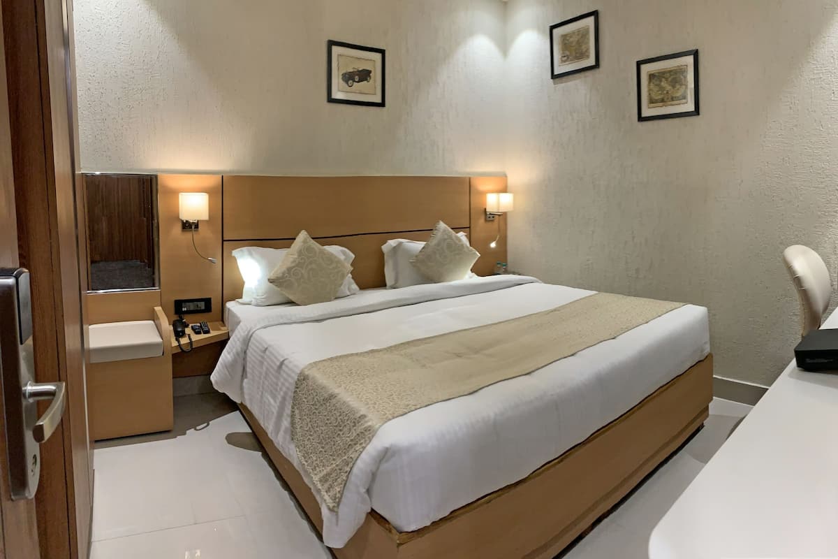 Una habitación de hotel con una cama grande, mesitas de noche, un escritorio y una silla.