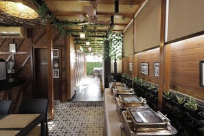 A restaurant interior with a long counter, wooden walls, and hanging plants.