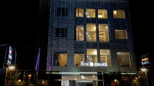 A multi-story building with the sign "SUN GRAND" at the entrance, featuring a modern design with illuminated string lights. - Hotel Sun Grand (Dehradun)