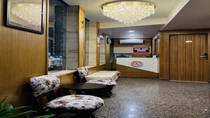 A hotel lobby with a reception desk, seating area, and a chandelier. - Hotel Sun Grand (Dehradun)