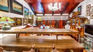 A spacious dining area with a large wooden table, surrounded by chairs. The room features wooden beams on the ceiling, a chandelier, and various framed artworks on the walls. - Gorgeous and Spacious Apartment Equipped with Unique and Valuable Furniture  (Split)