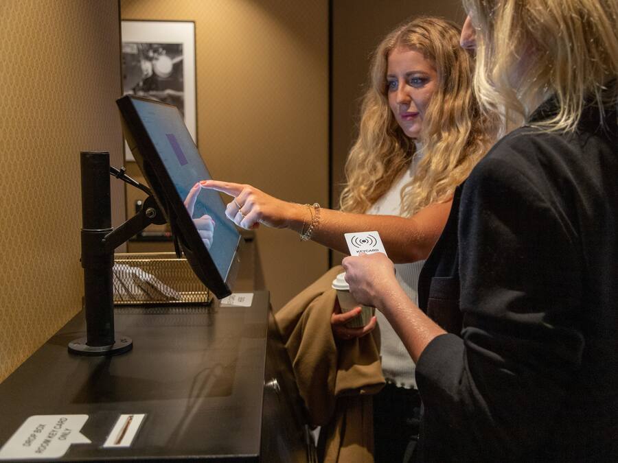 Una persona usando un quiosco digital en el vestíbulo de un hotel.