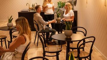 Un interior moderno con mesas y sillas redondas, una zona de bar y plantas en macetas.
