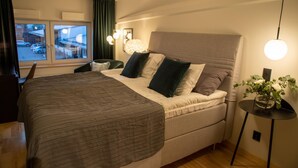 A bedroom with a large bed, a desk, and a window with curtains. - Hotell Syfabriken (Falkoping)