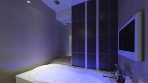A modern bathroom with a large bathtub, a mirror, and a shower area.