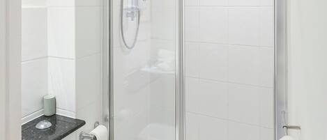 Moderni kylpyhuone, jossa on lasiseinällä varustettu suihku, wc ja pyyhekoukku.