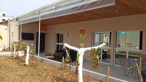 A modern building with a covered patio area, potted plants, and outdoor seating. - Residence Mturquoise T1 (Abidjan)