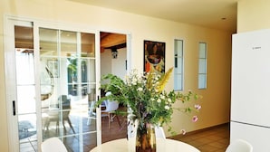 A modern kitchen with a white Bosch refrigerator, a dining table with two white chairs, and a vase with flowers on the table. - Perseidas House, Wonderfull house with pool and sea views. (Tijarafe)