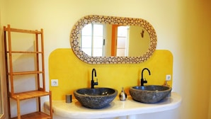 A bathroom with two stone sinks, a wooden shelf, and a mirror with a decorative frame. - Perseidas House, Wonderfull house with pool and sea views. (Tijarafe)