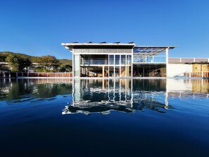 Um edifício moderno com fachada de vidro e piscina em frente.