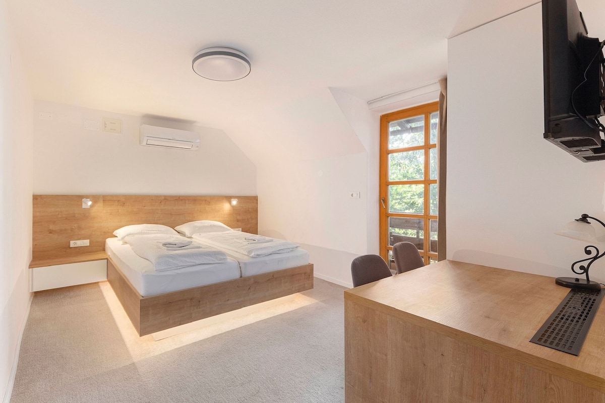 Quarto moderno com cama de madeira, escrivaninha e janela com vista.