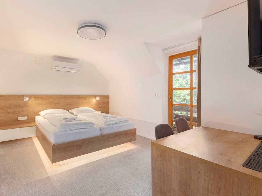 A modern bedroom with a wooden bed, a desk, and a window with a view.