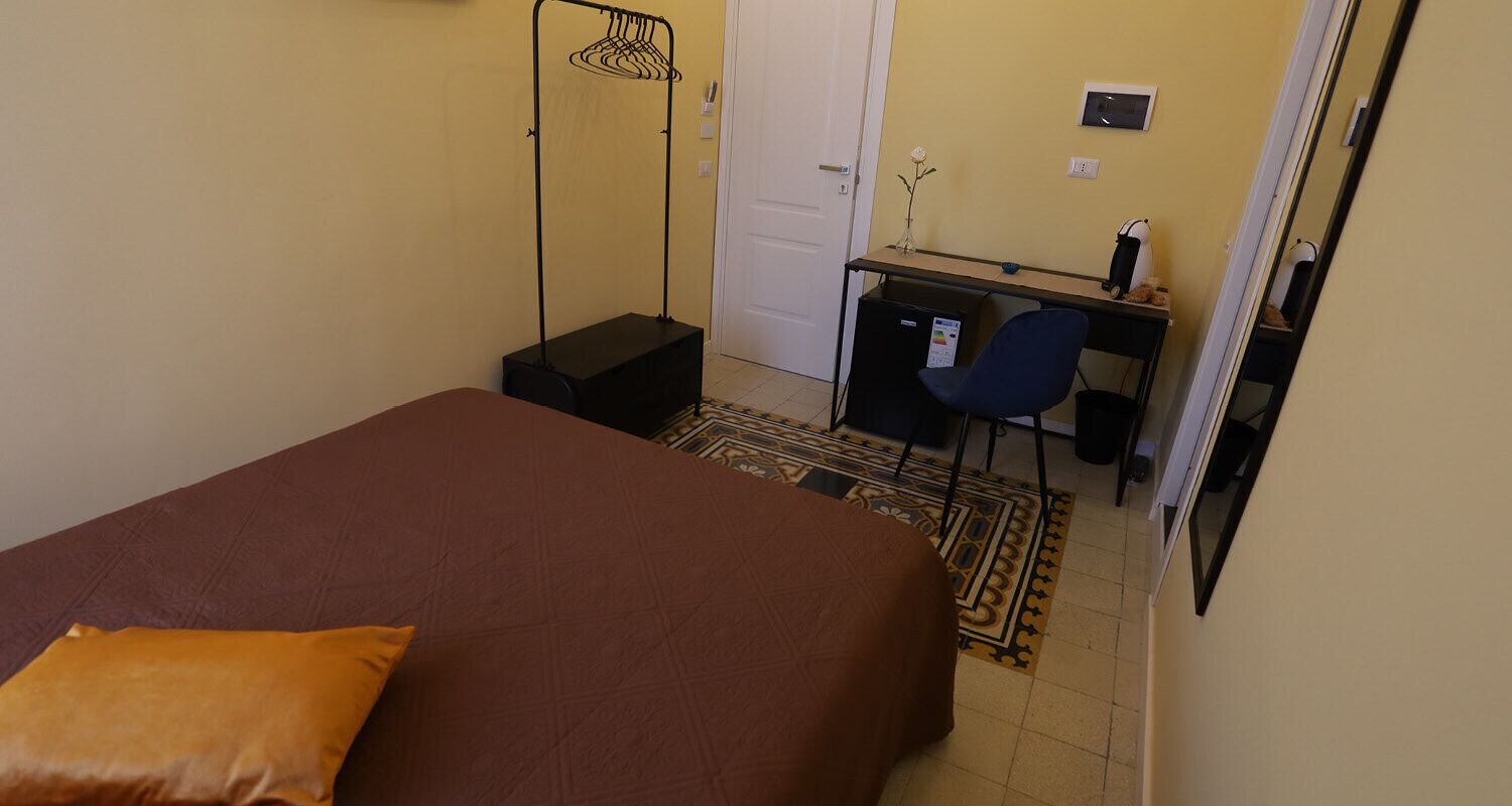 A bedroom with a bed, a desk, and a chair.