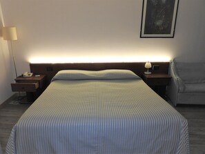 A hotel room with a bed, a nightstand with a lamp, a chair, and a framed picture on the wall. - Hotel Centrale (Trebaseleghe)