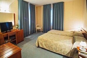 A hotel room with a bed, a desk with a television, a chair, and a lamp. - Hotel Centrale (Trebaseleghe)
