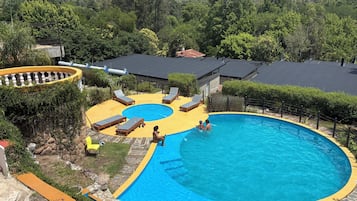 Una piscina de borde curvo, rodeada de sillones de descanso y una terraza amarilla.