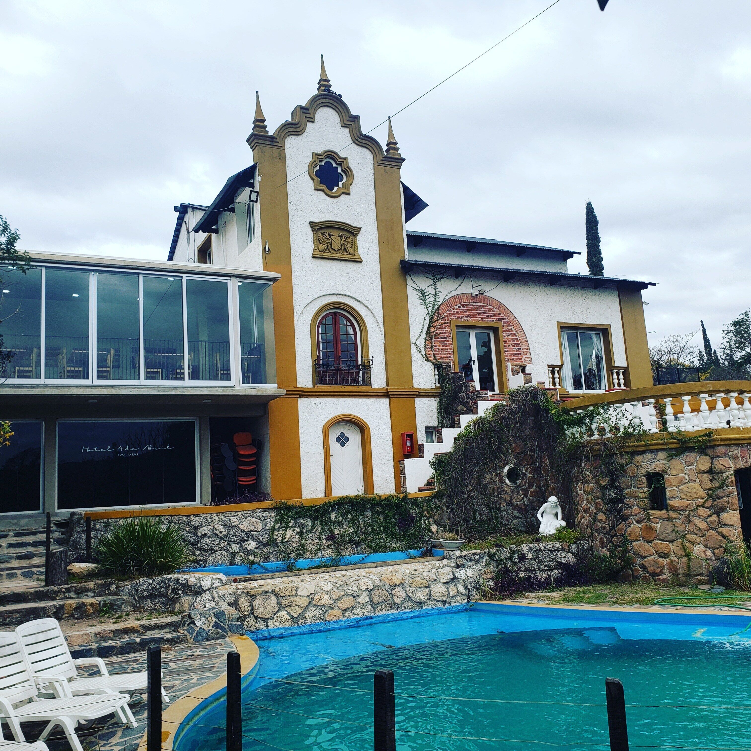 A hotel with a pool, a staircase leading to the entrance, and a view of the surrounding landscape.
