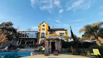 Un edificio con una piscina grande, un arco de piedra y una torre del reloj.