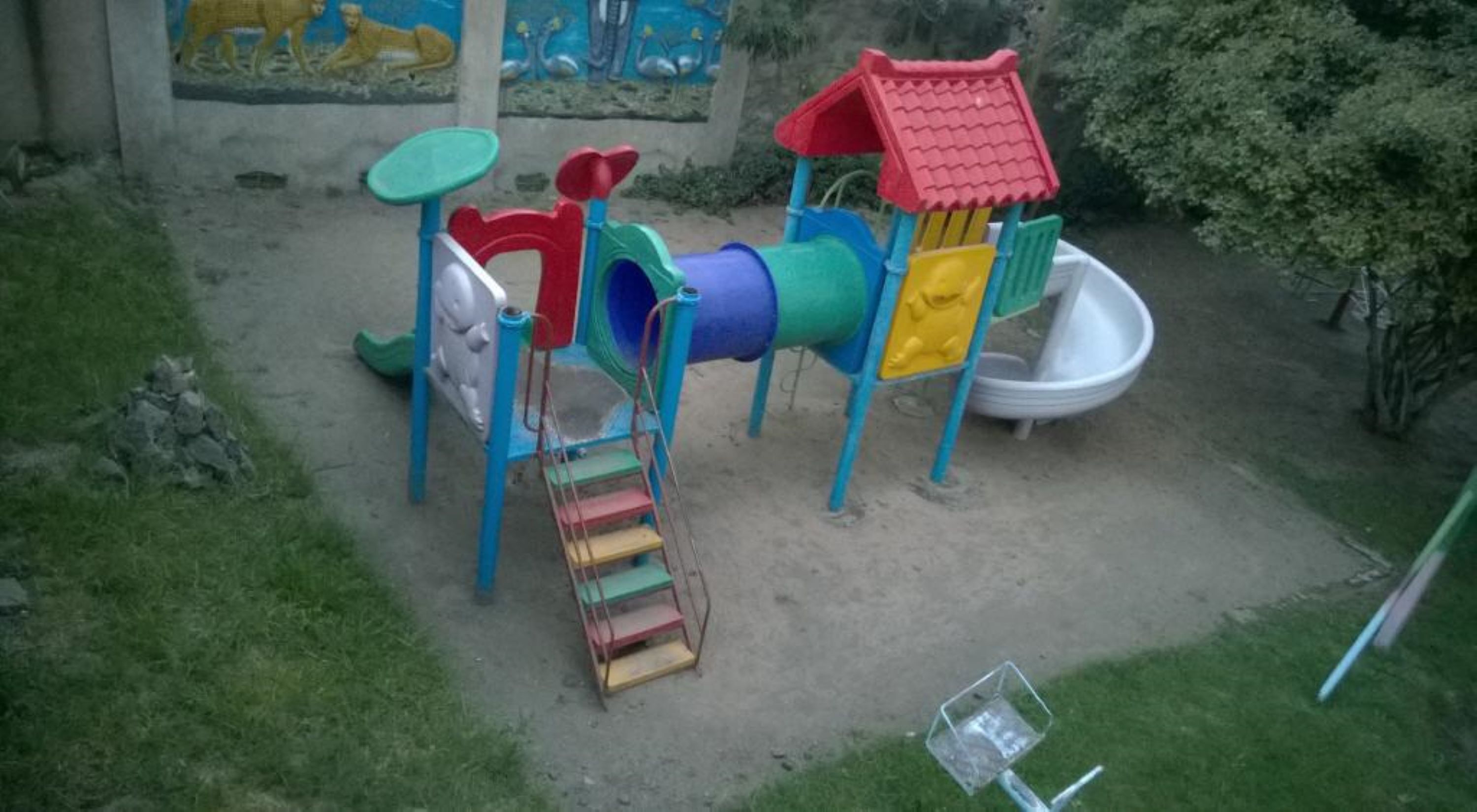 A playground with a slide, climbing structure, and a small ramp.