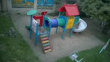A playground with a slide, climbing structure, and a small ramp.