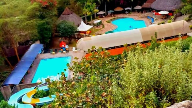 A resort with multiple swimming pools, a water slide, and thatched-roof structures. - Panorama Park Hotel (Naivasha)