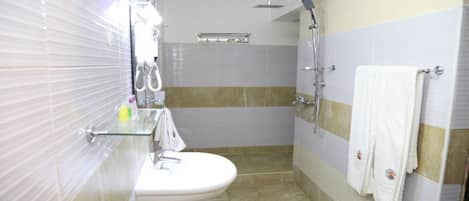 Un baño con lavamanos, espejo, toallero, ducha y paredes de azulejos.