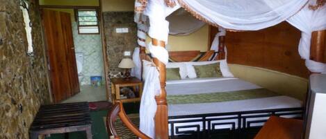 Una habitación con cama, mesita de noche, lámpara y un banco de madera.