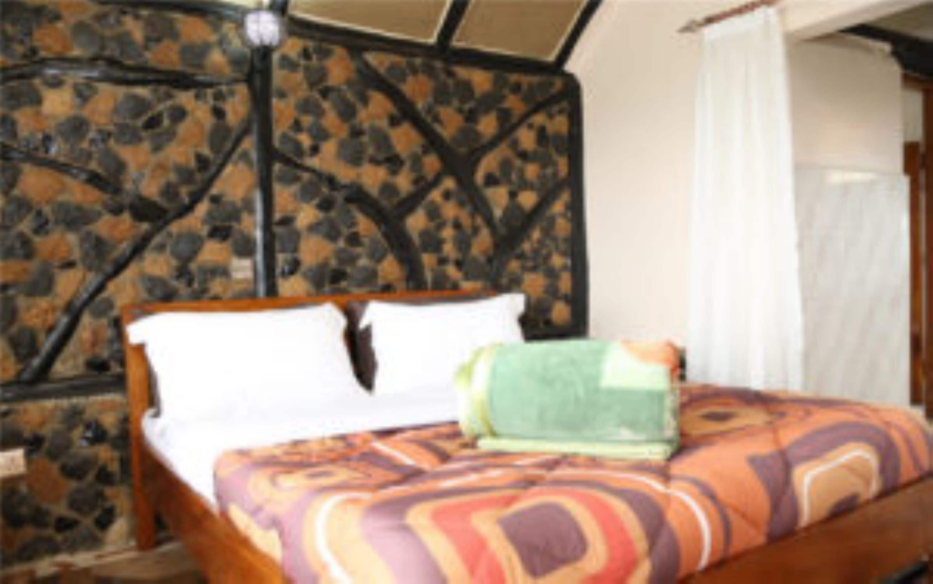 Un lit avec une couvre-lit à motifs, une tête de lit en bois et une table de chevet avec une lampe.