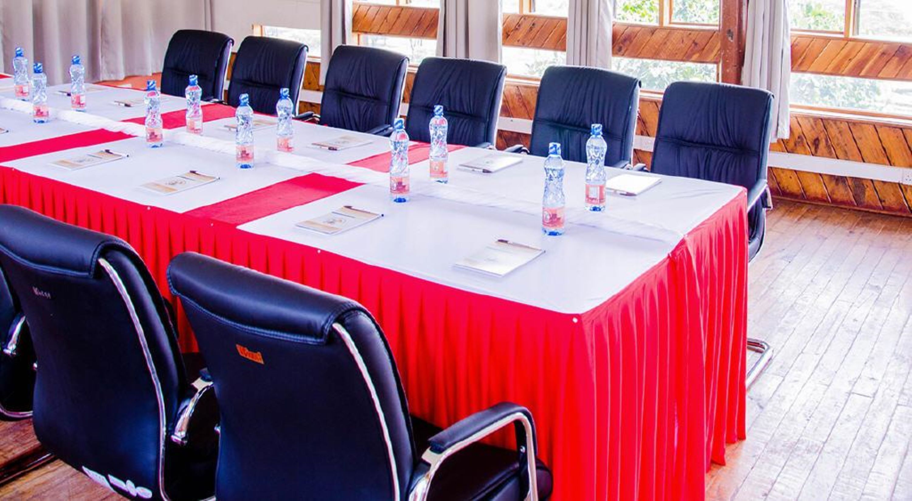 A conference room with a long table, black chairs, and water bottles.